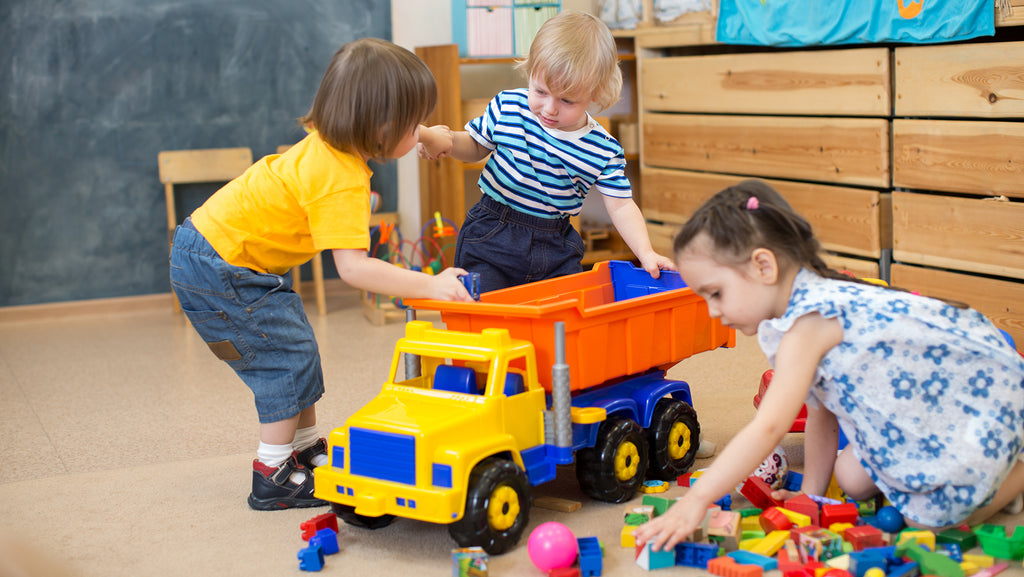 Three children are playing with goods carrier toy